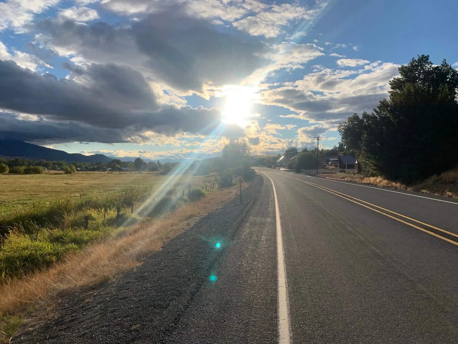 Low sun flaring over an empty road and dry fields